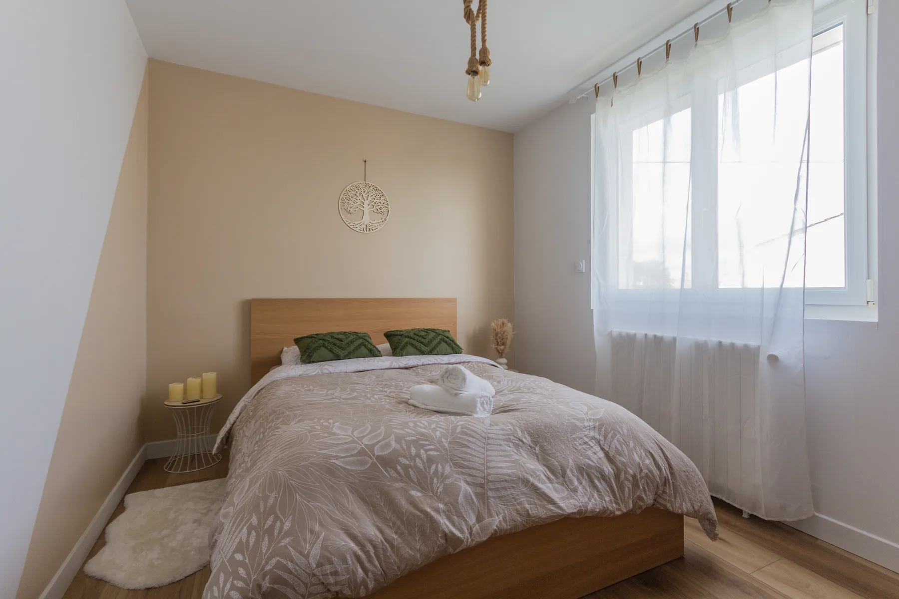 Chambre après rénovation avec peinture claire, tête de lit beige et sol bois