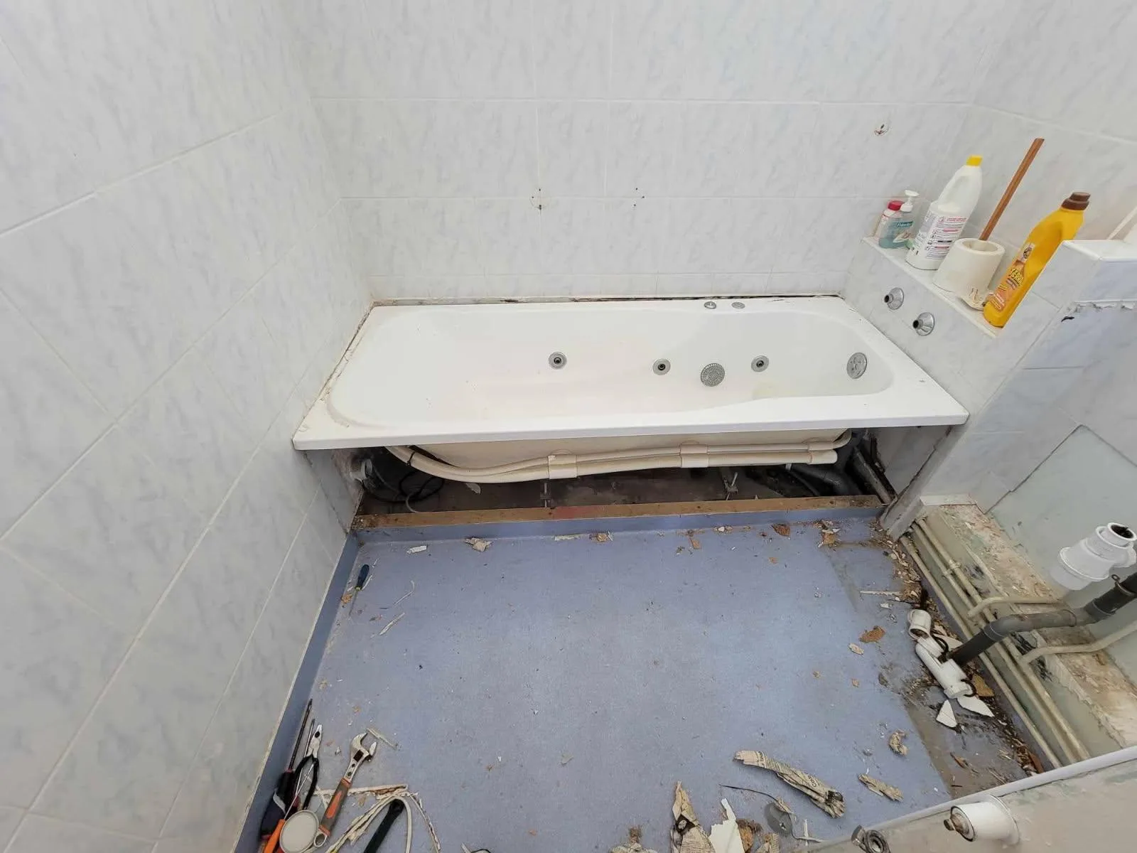 Salle d'eau avant intervention avec baignoire déposée et sol en préparation