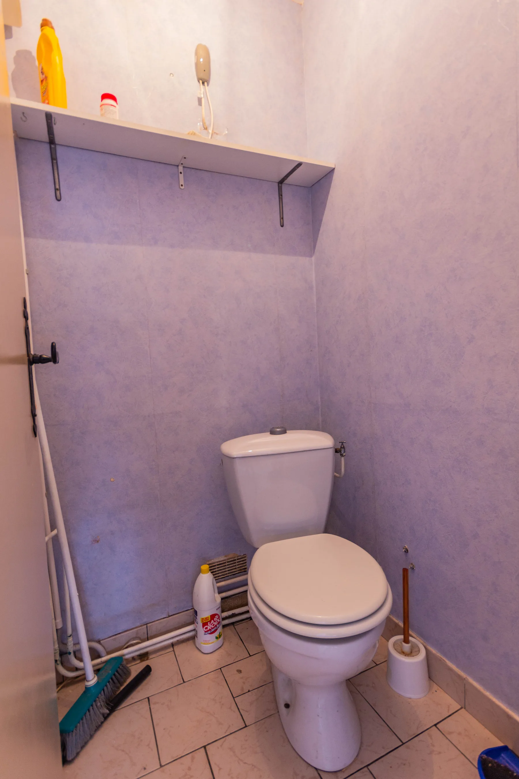 WC avant rénovation avec murs bleutés, étagère haute et ancien carrelage